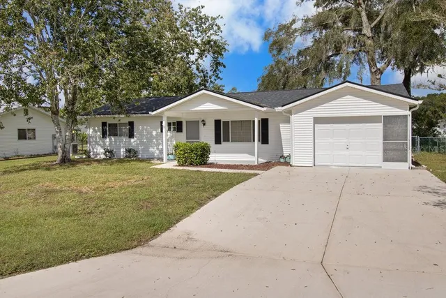 a front view of a house with a garden and trees
