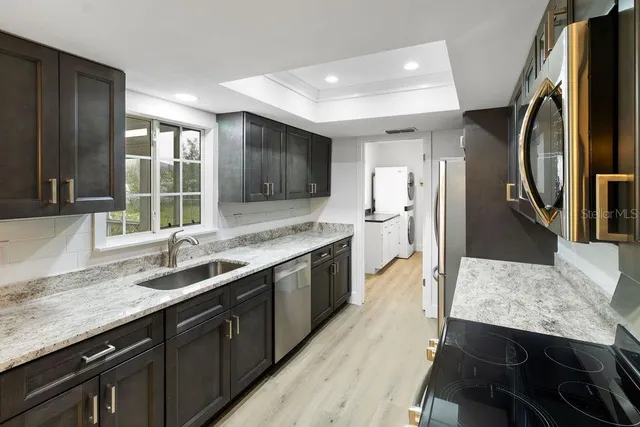 a large kitchen with a stove a sink dishwasher a refrigerator and wooden floor