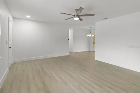 an empty room with wooden floor and a ceiling fan