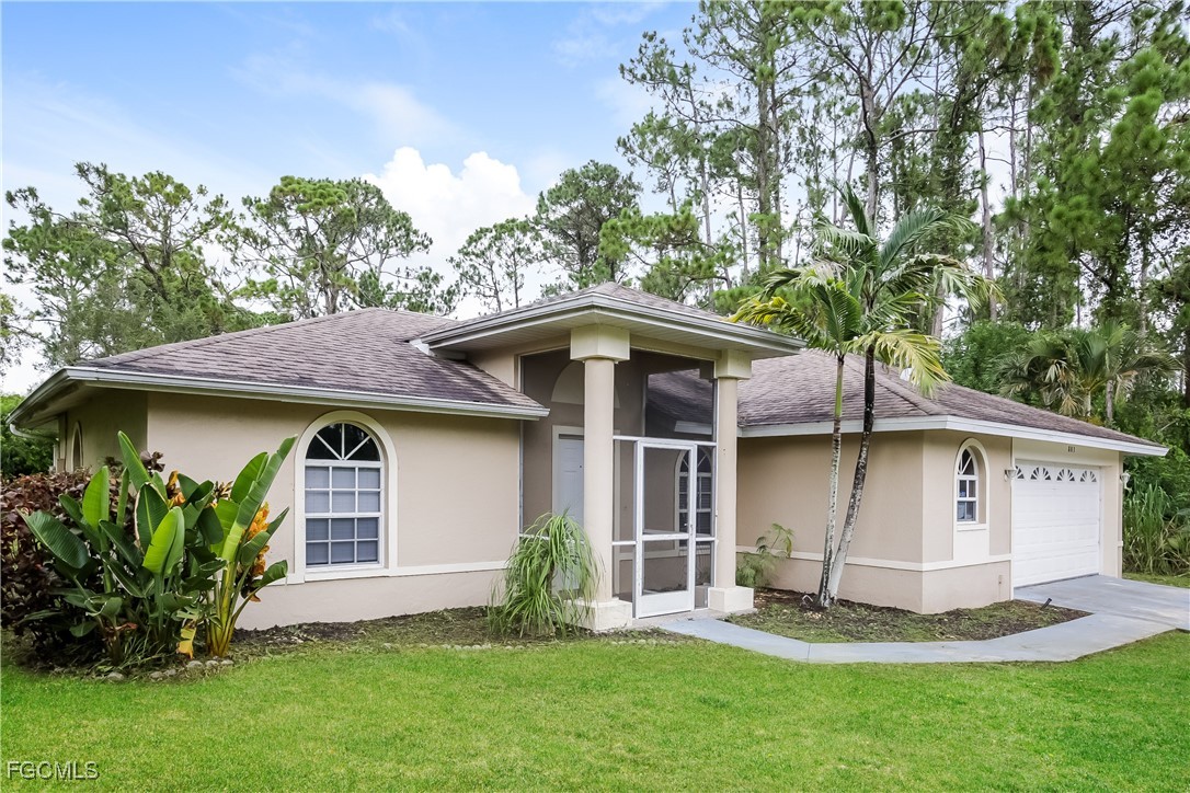 803 Hamilton Avenue Lehigh Acres, FL 33972 - Photo 2 of 16 a front view of a house with a garden and plants
