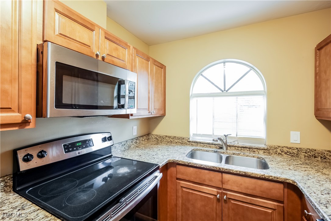 803 Hamilton Avenue Lehigh Acres, FL 33972 - Photo 7 of 16 a kitchen with granite countertop a stove a sink and a microwave