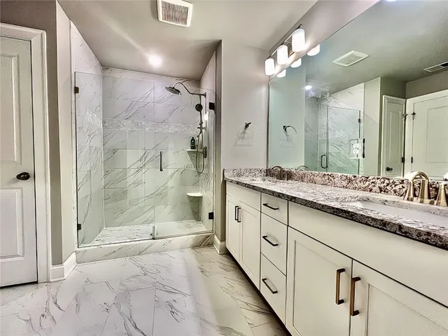 a bathroom with a granite countertop sink a large mirror and a shower