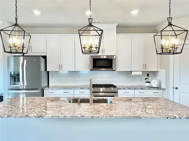 a kitchen with stainless steel appliances granite countertop a sink a stove top oven a counter space and cabinets