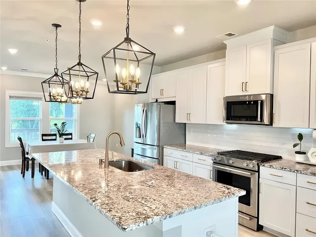 a kitchen with kitchen island granite countertop a sink a stove and chairs