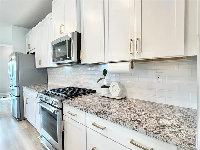 a kitchen with granite countertop white cabinets and stainless steel appliances