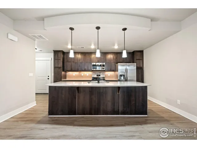 a kitchen with a sink a refrigerator and wooden floor