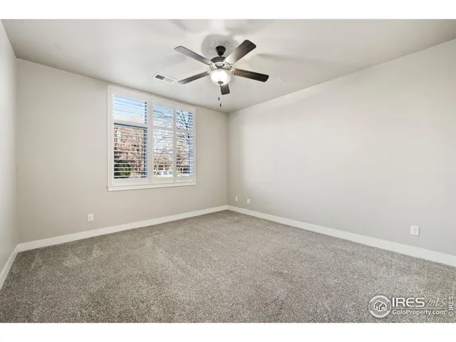 an empty room with windows and ceiling fan