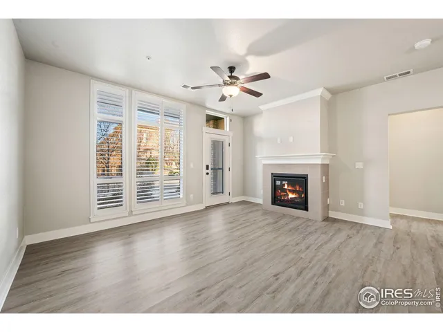 a view of an empty room and kitchen with fireplace ceiling fan