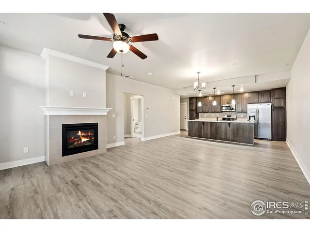 a view of an empty room with wooden floor and fireplace