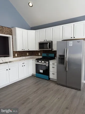 a kitchen with granite countertop white cabinets and stainless steel appliances