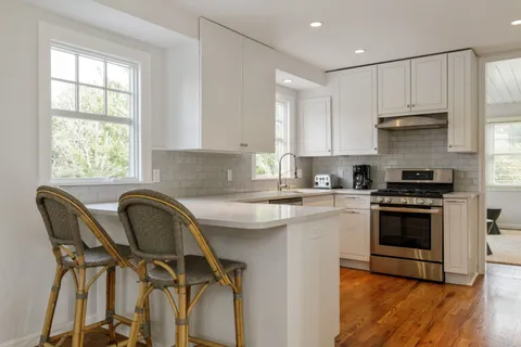 a kitchen with a stove a sink and white cabinets