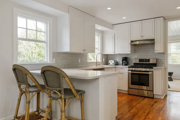 a kitchen with a stove a sink and white cabinets