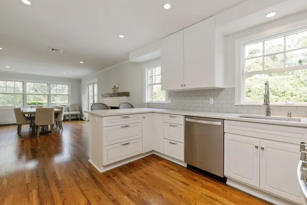 a kitchen with white cabinets and wooden floors