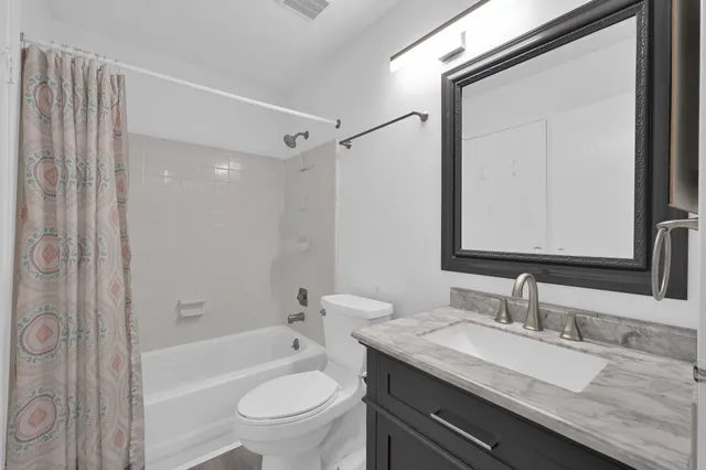 a bathroom with a granite countertop sink a toilet and shower