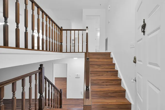 a view of staircase with lots of frames on wall and wooden floor