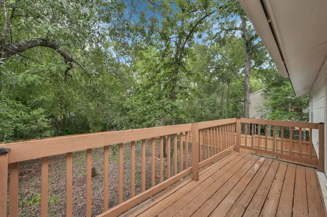a balcony with wooden floor and trees in the back