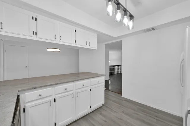 a kitchen with granite countertop white cabinets and stainless steel appliances
