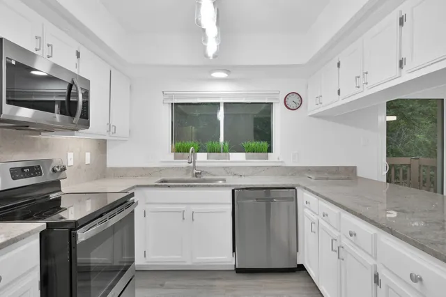 a kitchen with granite countertop kitchen island a sink stainless steel appliances and white cabinets