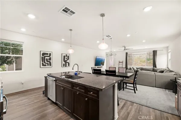a kitchen with stainless steel appliances granite countertop a stove a sink a dining table and chairs with wooden floor