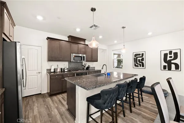 a kitchen with stainless steel appliances granite countertop a stove a refrigerator a kitchen island a sink cabinets and a dining table