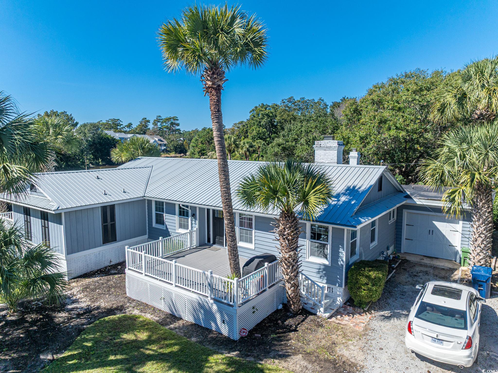 View of front of house with a chimney, a deck, and a metal roof