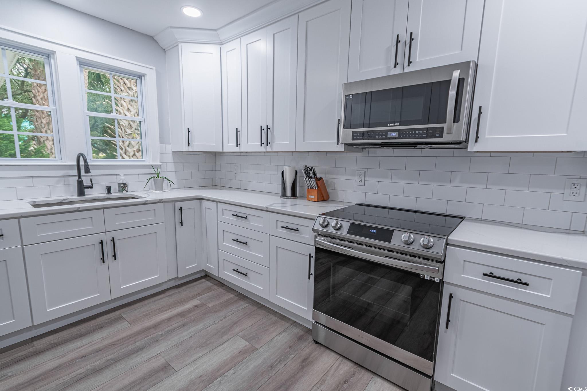5307 North Ocean Boulevard Myrtle Beach, SC 29577 - Photo 16 of 39 Kitchen featuring appliances with stainless steel finishes, white cabinets, decorative backsplash, light stone counters, and recessed lighting