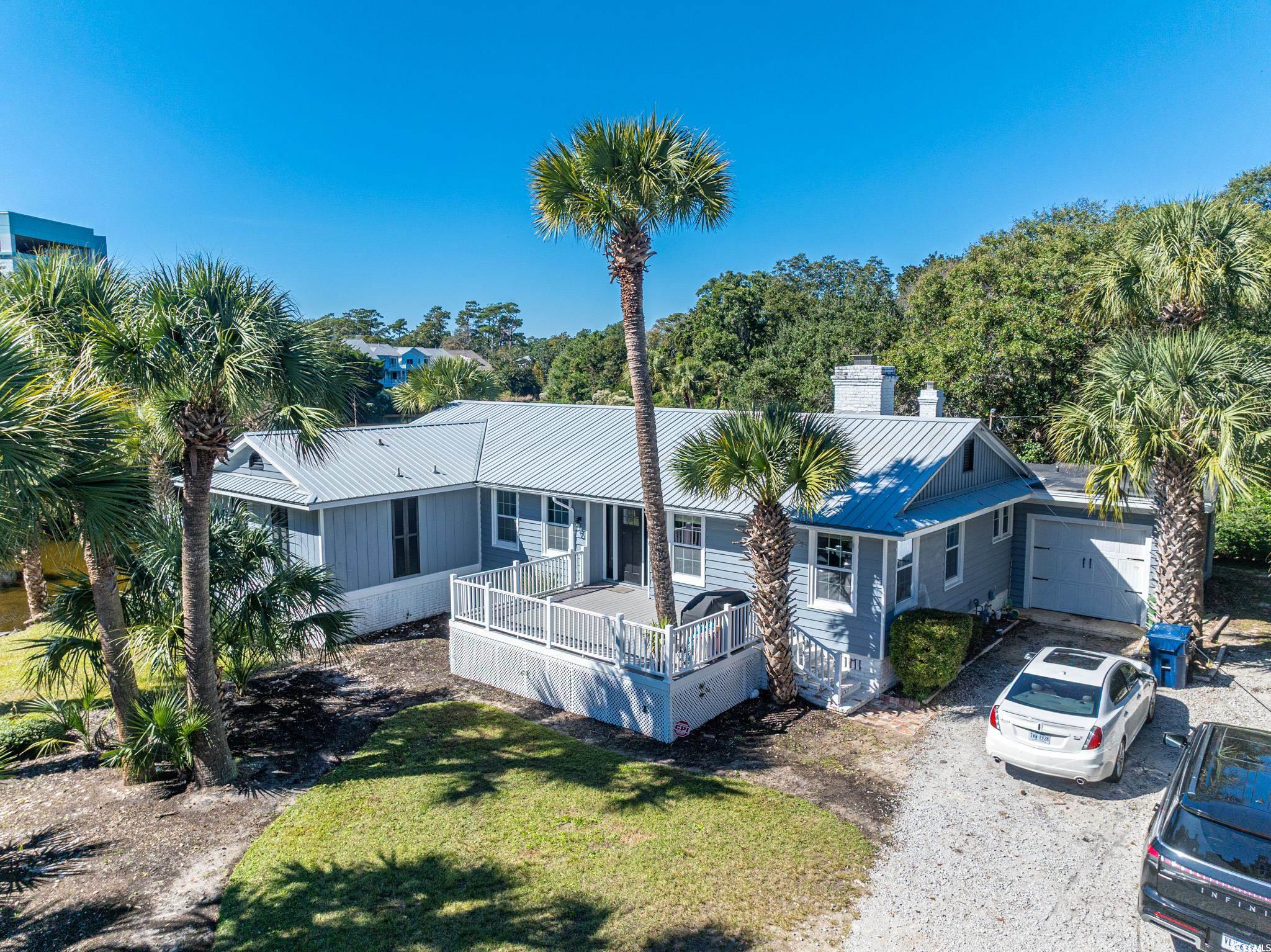 5307 North Ocean Boulevard Myrtle Beach, SC 29577 - Photo 38 of 39 View of front of home featuring a wooden deck, a chimney, a metal roof, gravel driveway, and a front lawn