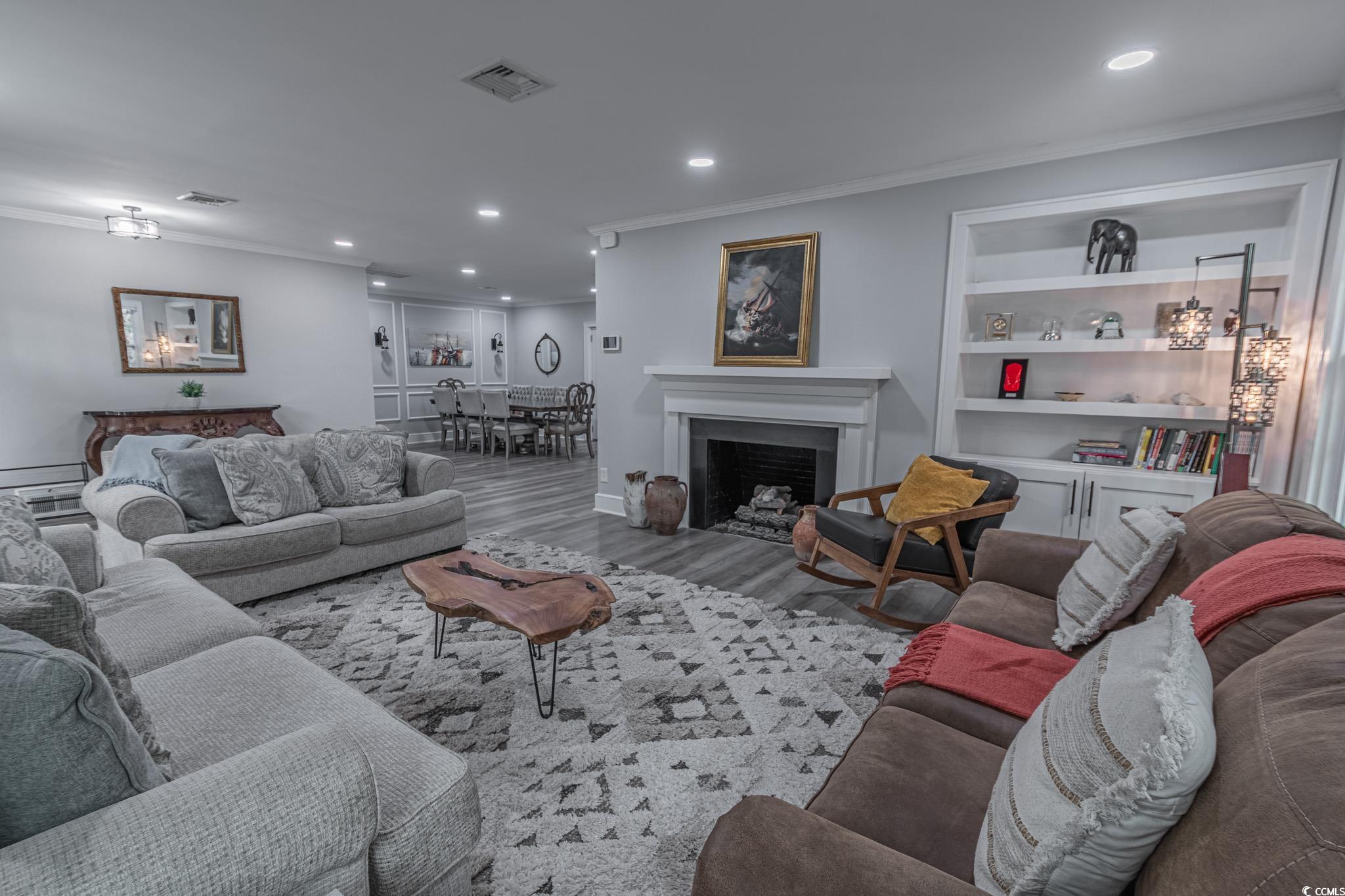 5307 North Ocean Boulevard Myrtle Beach, SC 29577 - Photo 9 of 39 Living room with crown molding, a fireplace, recessed lighting, wood finished floors, and built in shelves