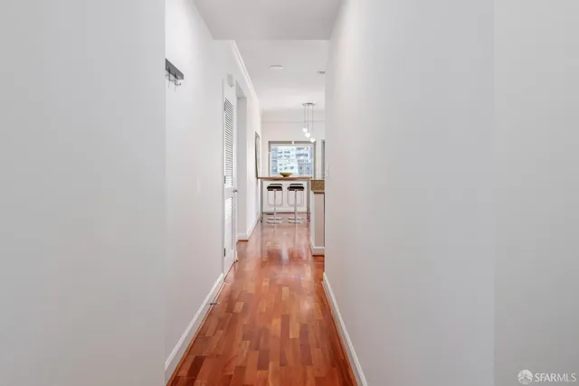 a view of a hallway with wooden floor and a bathroom