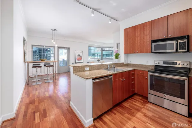 a kitchen with stainless steel appliances kitchen island granite countertop wooden floors and wooden cabinets