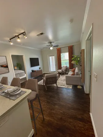 a living room with couches and kitchen view with wooden floor