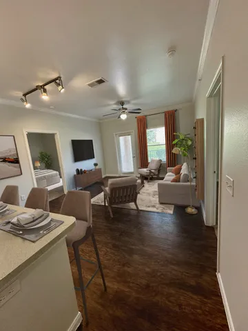 a living room with couches and kitchen view with wooden floor
