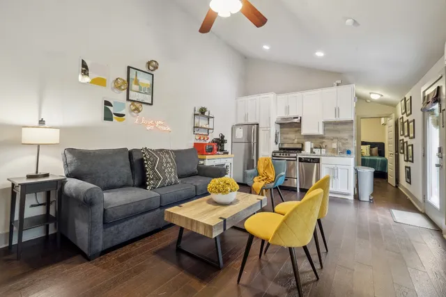 a living room with stainless steel appliances kitchen island granite countertop furniture and a wooden floor