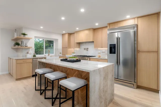 a kitchen with stainless steel appliances granite countertop a table chairs sink refrigerator and cabinets