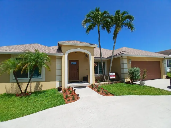 a front view of a house with a yard and palm tree