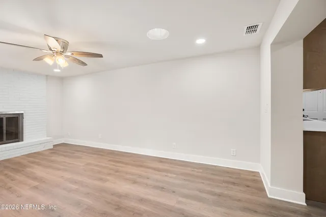 an empty room with wooden floor fan and windows