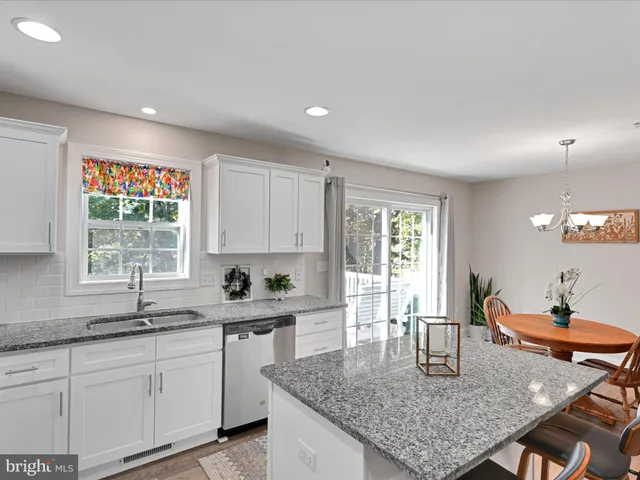 a kitchen with granite countertop a sink white cabinets a window and a counter space