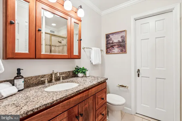 a bathroom with a granite countertop sink and a toilet