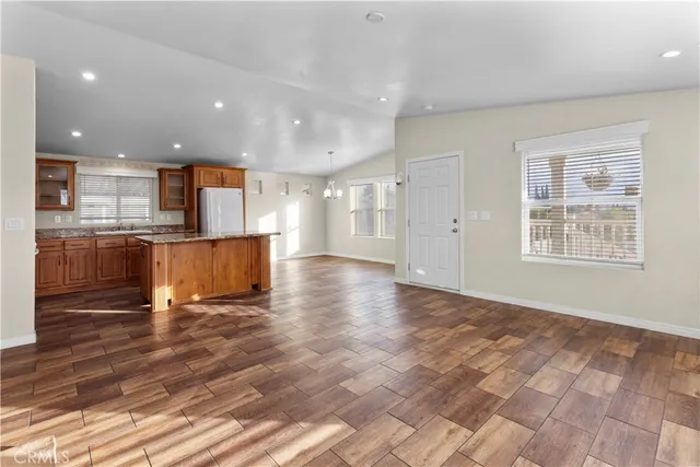 a view of a kitchen with kitchen island granite countertop wooden floor stainless steel appliances and cabinets