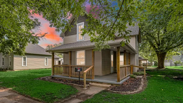 a view of a house with a yard and a large tree