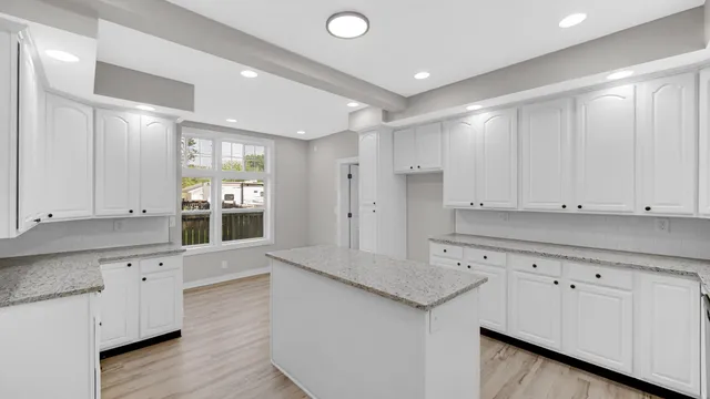 a kitchen with granite countertop white cabinets and white appliances