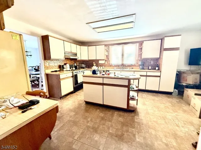 a kitchen with stainless steel appliances granite countertop a stove top oven a sink dishwasher and white cabinets next to a window