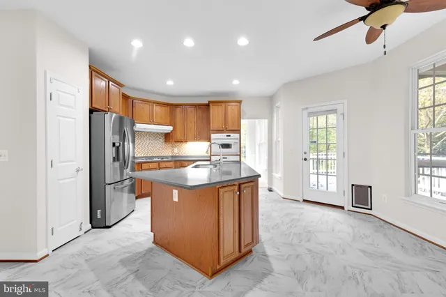 a kitchen with stainless steel appliances granite countertop a refrigerator a sink a stove and oven