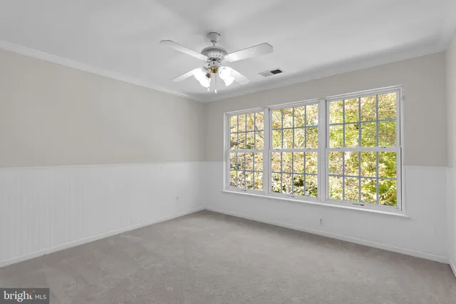 an empty room with a chandelier fan and closet area