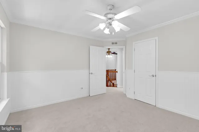 an empty room with chandelier fan and windows