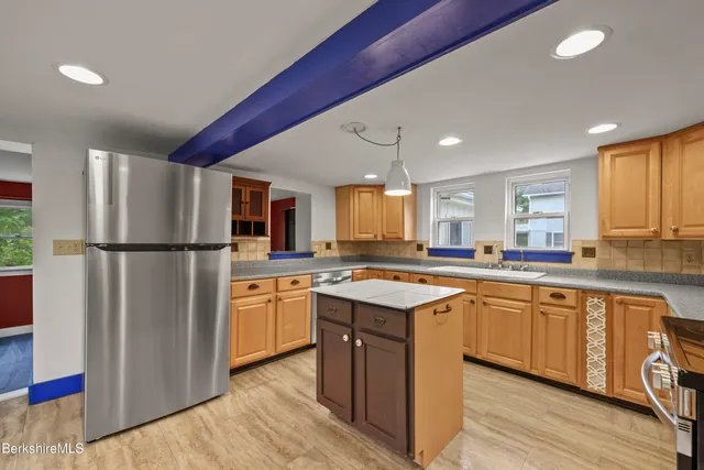 a kitchen with stainless steel appliances granite countertop a refrigerator a sink dishwasher a stove and white countertops with wooden floor