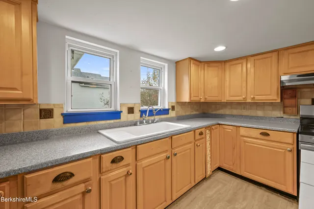 a kitchen with granite countertop white cabinets sink and window