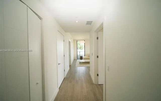 a view of a hallway with wooden floor and closet area
