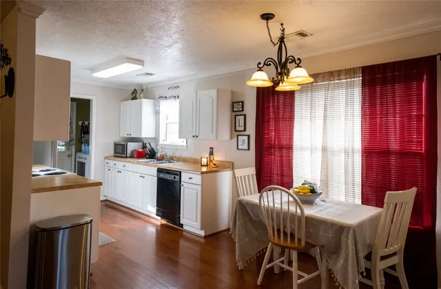 a open dining room with stainless steel appliances kitchen island granite countertop furniture and a chandelier