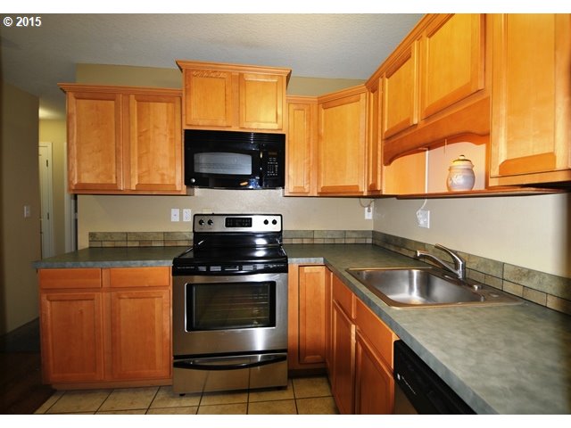 13320 Southwest Allen Boulevard, Unit 310 Beaverton, OR 97005 - Photo 7 of 18 a kitchen with granite countertop a sink a stove and microwave